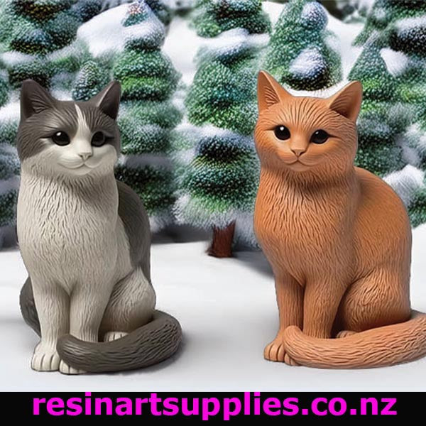 Two cat figurines in front of snow-covered trees with 'resinartsupplies.co.nz' branding.