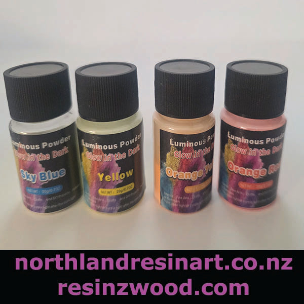 Four bottles of luminous powder with black lids on a white background, featuring colors like Sky Blue, Yellow, Orange, and Red.