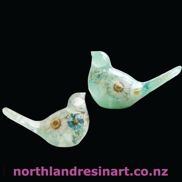 Two green resin birds with floral designs on a black background, featuring the brand 'northlandresinart.co.nz'.
