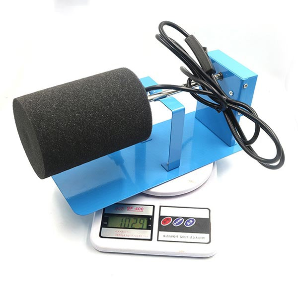 A Single Cup Turner with an attached power cable, shown next to a digital scale on a white background.