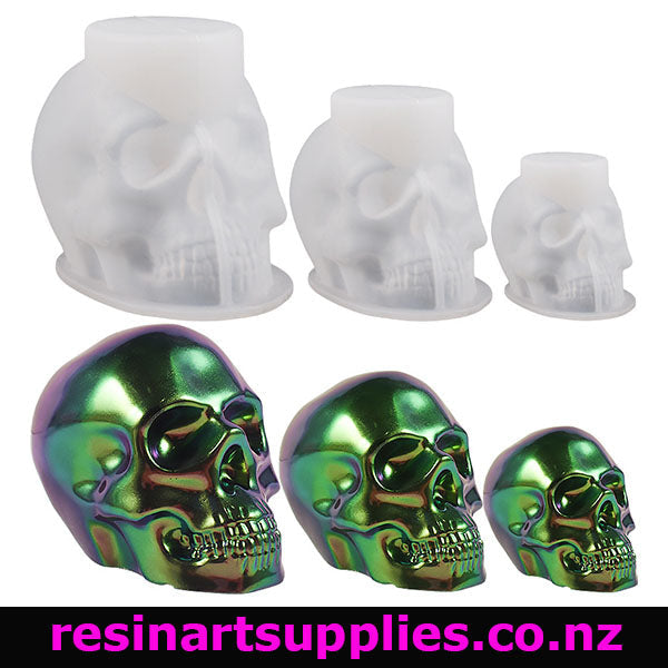 Three silicone moulds of human skull that are off-white on a white back ground with three green heads that vary in size in the bottom row.