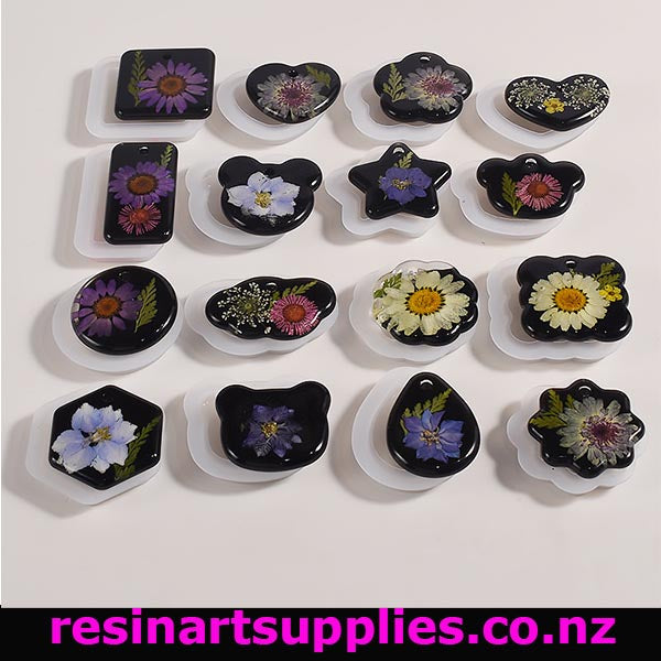 Silicone Pendant / Keyring Moulds times by sixteen pieces sitting on the moulds with pinky white background. Contains the words Resin Art Supplies . co.nz on a black background as being the domain name
