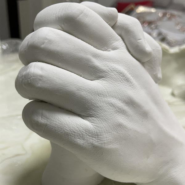 White ceramic hand sculpture on a plain background