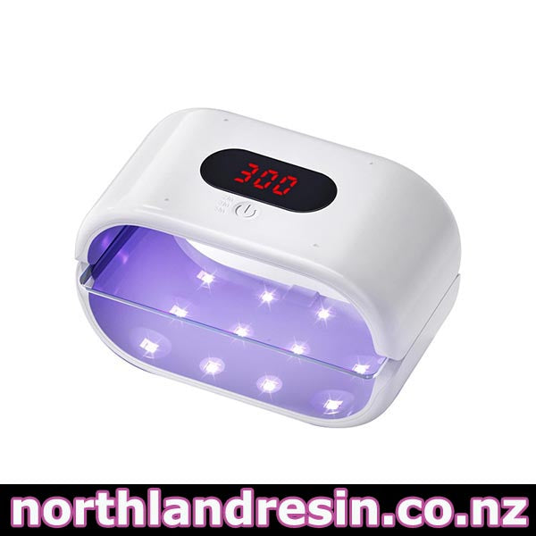 A white UV LED nail and resin lamp with a digital display showing 300 and a purple light glow inside, set against a plain white background with a website watermark at the bottom. 